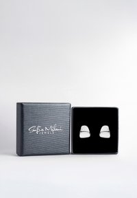 Silverfärgade stiftörhängen i en svart sammetinsats, presenterade i en texturerad mörkgrå låda med "Sofia Milani Jewels"-logotyp.