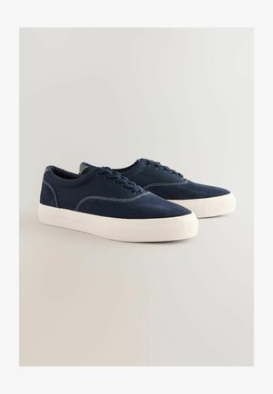 Dunkelblaue Leinenschuhe mit weißen Gummisohlen, abgerundeten Zehen und kontrastierenden weißen Nähten. Verfügt über sechs Ösen und einen gepolsterten Kragen.