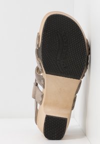 Sandale en daim beige avec semelle extérieure en caoutchouc noir, équipée de deux sangles réglables et d'une quincaillerie décorative. Taille 37 indiquée sur la semelle.