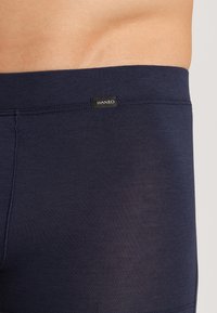 Navy siniset bokserit, jotka on valmistettu sileästä, venyvästä kankaasta; niissä on pehmeä vyötärönauha, jossa on pieni musta HANRO-logo takana.