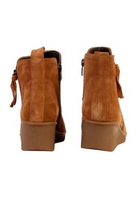 Suède enkelboots in warm oranje met een gladde textuur, voorzien van een lage blokhak, een zijrits en een achterste looplus voor gemakkelijk aantrekken.