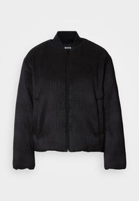 Veste bomber noire texturée avec fermeture éclair intégrale à l'avant, col côtelé et manches longues, présentée sur un fond clair uni.