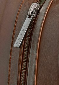 Bruine lederen ritsluiting met zilveren halsband, met een gestructureerd oppervlak en contrasterende bruine stiksels langs de randen.