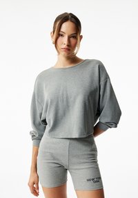 Szara, krótkie bluza z luźnymi rękawami, w zestawie z dopasowanymi, wysokimi na biodrach, żeberkowymi szortami z haftem "NEW YORK 1994".