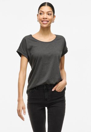 Mörkgrå t-shirt med kort ärm och rundad halsringning, mjuk textur, avslappnad passform, matchad med svarta jeans. Modellen poserar med ena handen i fickan.