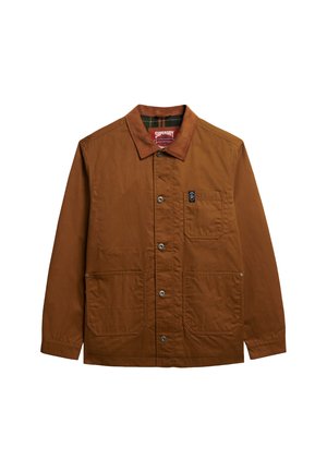 Bruine katoenen jas met een knoopsluiting aan de voorkant, twee grote voorzakken, een borstzak en een contrasterende kraag. Bevat subtiele brandingdetails.