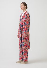 Kimono stylizovaný župan s květinovým vzorem a odpovídajícími kalhotami v živých růžových, modrých a zelených barvách, vyrobený z lehké tkaniny, s páskem na zavázání v pase.
