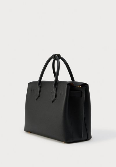 Μαύρη τσάντα χειρός από υφή δέρματος με δύο στρογγυλά χερούλια, δομημένο ορθογώνιο σχήμα και χρυσούς μεταλλικούς ποδίσκους σε λευκό φόντο.