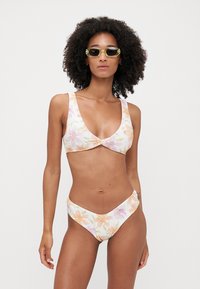 Ensemble de bikini floral comprenant un bralette rembourré avec des bretelles larges et un bas taille haute. Le matériau est lisse avec des couleurs pastel et une légère brillance.