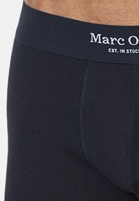 Svarta ribbade boxerkalsonger med en mjuk midja som har vit "Marc O'Polo" branding. Tyget har en slät yta och en nära passform.