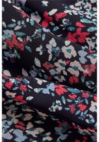 Tissu noir avec des plis ornés de petits motifs floraux rouges, blancs, verts et bleus, disposés de manière rapprochée.