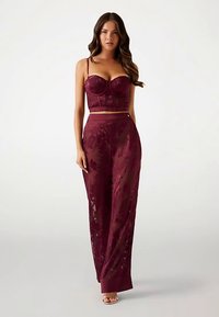 Bordeauxfarbenes zweiteiliges Set bestehend aus einem eng anliegenden BH mit Bügel und durchsichtigen, breit geschnittenen Hosen mit floralem Muster.