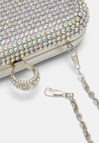 Metaliczna kopertówka ozdobiona wielobarwnymi kryształkami, wyposażona w zaokrąglony uchwyt, srebrny łańcuch i bezpieczne zapięcie.