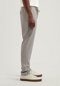 Grijze joggingsbroek met een slim fit, gemaakt van textuurstof, met een elastische tailleband en een koord, gecombineerd met witte sneakers.