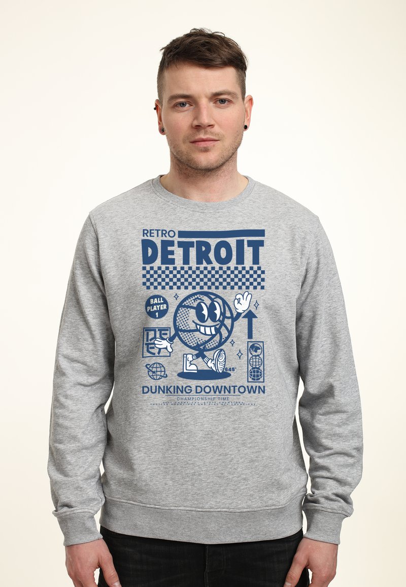 Felpa grigia con un design grafico retro. Il design include un personaggio di basket sorridente e la scritta "DETROIT" in bold blu.