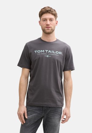 Camiseta de algodón gris con mangas cortas que presenta el texto "TOM TAILOR" en azul claro, escote redondo y ajuste relajado.