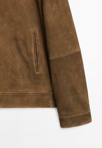 Brun mockaskinnjacka med en slät textur, rak skärning, sidficka och kontrasterande krage.