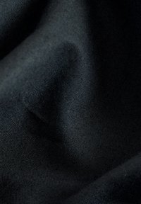 Tessuto nero con una texture liscia, caratterizzato da una superficie leggermente riflettente e una trama fine, che crea ombre e profondità sottili.