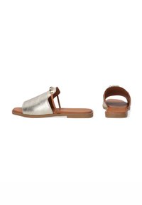 Metallic gyldne slidesandaler med en glat overflade, åben tå og flad tan sål. Har dekorative hardware-detaljer på vampen.