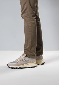 Beigen ja harmaan sävyiset tennarit, joissa on mokka- ja tekstiilipäällinen, paksu kermaisen värinen pohja, näkyvät nauhat ja kuvioitu kulutuspinta.