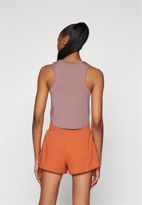 Canotta di un leggero color malva con scollo rotondo e senza maniche, abbinata a pantaloni corti arancioni con vita elasticizzata e una vestibilità comoda.