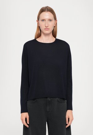Navy long-sleeve sweater with a round neckline, relaxed fit, soft texture, and straight hem, paired with black high-waisted pants.