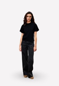 Zwart cropped t-shirt met korte mouwen, gecombineerd met hoge taille zwarte wijde jeans. Zachte textuur, minimalistisch ontwerp en geen zichtbare patronen.