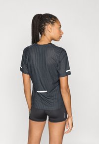 Czarna sportowa koszulka z pionowymi paskami, krótkimi rękawami oraz białymi akcentami na ramionach i plecach, w zestawie z czarnymi szortami.