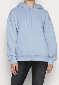 Felpa leggera blu chiaro realizzata in tessuto morbido, con tasca a canguro, cappuccio con cordino e polsini a costine. Design a vestibilità rilassata.