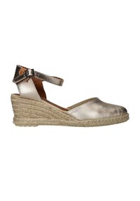 Espadrille de cuña plateada metálica con parte superior texturizada, correa al tobillo y suela de yute trenzado. Presenta un diseño de puntera redondeada y tacón bajo.