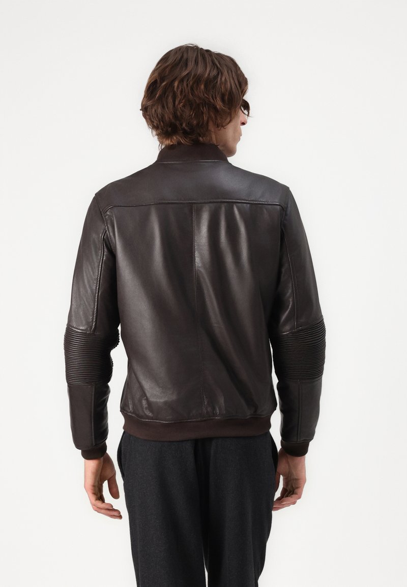 Bruine leren jacket met ribbelaccenten op de mouwen, een getailleerd ontwerp en een zachte textuur, voorzien van een eenvoudige kraag en ritssluiting.