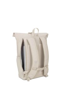Beige roll-top backpack with padded adjustable straps, chest buckle, mesh side pocket, top handle, and a partially open zipper revealing a laptop sleeve.