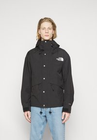 Sort vandtæt jakke med hætte, frontknaplukning, to nederste lommer, justerbare snoretræk og The North Face-logo på brystet.