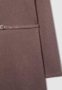 Tessuto brown a coste con vita regolabile, caratterizzato da una fibbia e occhielli argentati, e un design elegante con maniche lunghe.