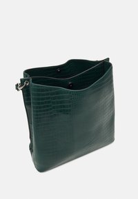 Green crocodile-patterned leather bag with a rectangular shape, open top, and two internal pockets. Features silver hardware and black buttons.