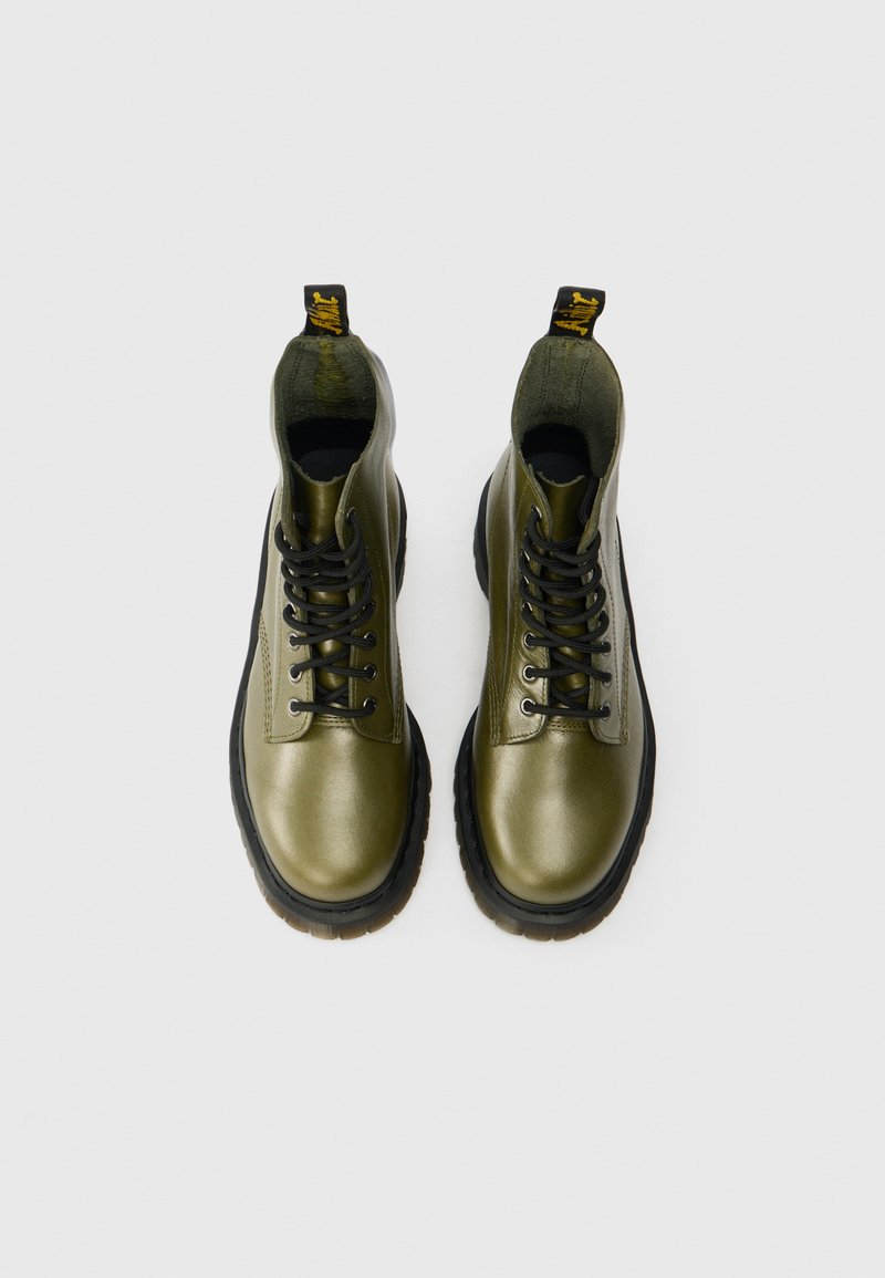 Olivgrüne Leder-Stiefeletten mit schwarzen Schnürsenkeln, runder Spitze und dickem schwarzen Gummisohle; mit Zuglasche auf der Rückseite.