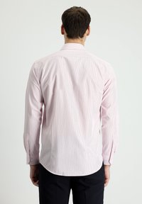 Helles rosa Langarmhemd mit vertikalen weißen Streifen, mit Knopfmanschetten und asymmetrischem Saum, aus glattem, gewebtem Stoff.