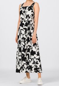 Czarna i biała kwiatowa sukienka midi z kwadratowym dekoltem, szerokimi ramiączkami i sylwetką w kształcie litery A. W połączeniu z białymi trampkami.
