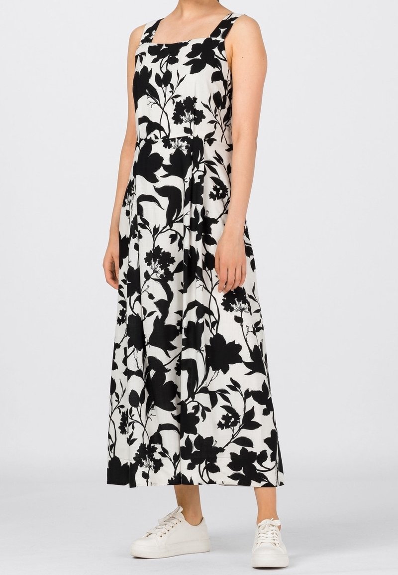Czarna i biała kwiatowa sukienka midi z kwadratowym dekoltem, szerokimi ramiączkami i sylwetką w kształcie litery A. W połączeniu z białymi trampkami.