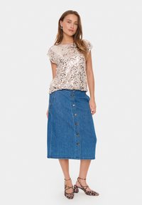Top a maniche corte in rosa gold con paillettes, abbinato a una gonna in denim con bottoni al fronte e tacchi a punta con stampa leopardata.