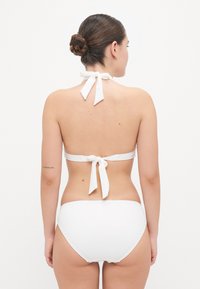 Hvit bikiniset som har halterneck med knyttinger og mid-rise bunn, glatt tekstur og ensfarget design.