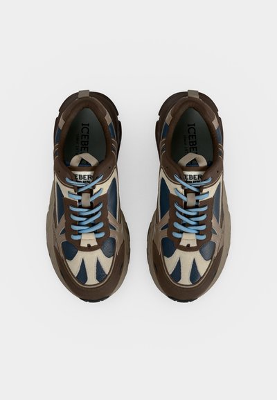 Paire de baskets marron, beige et bleu marine avec des lacets bleu clair vue de dessus sur fond blanc.