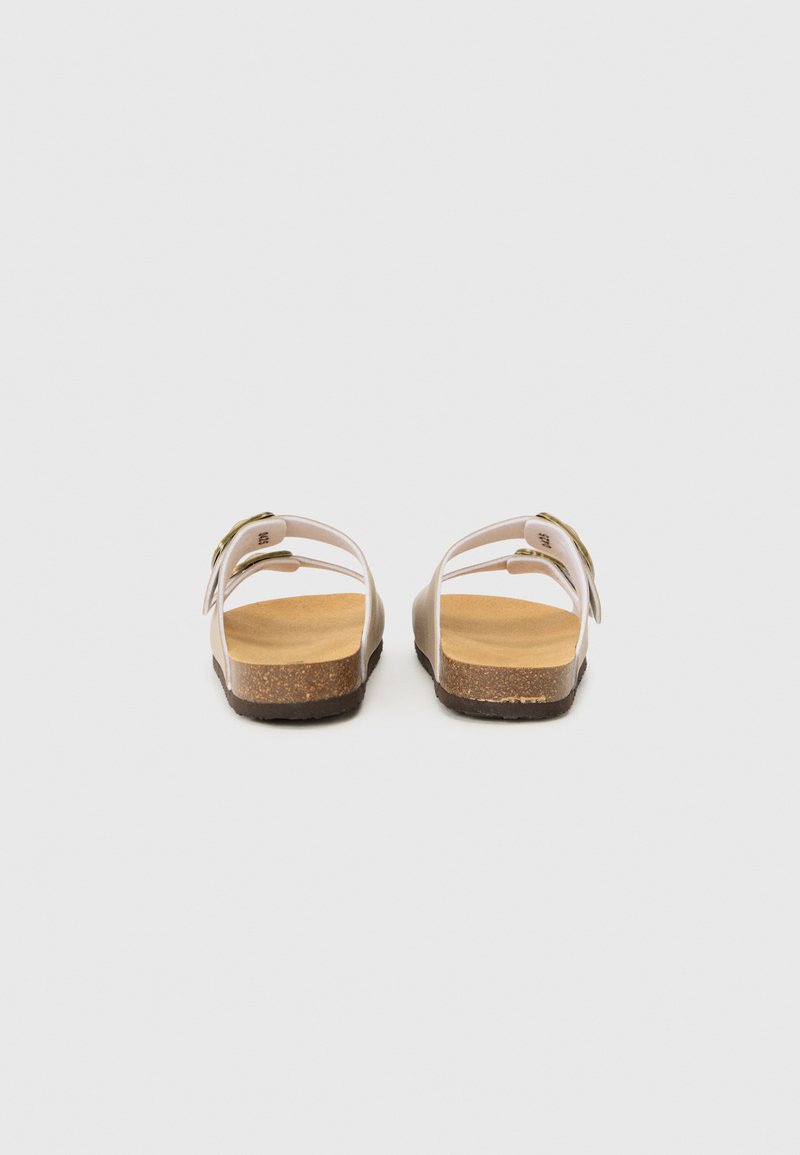 Sandales roses à lanières avec une semelle en liège et une semelle extérieure en caoutchouc. Conçues avec un accent de boucle sur la lanière et une semelle plate pour le confort.