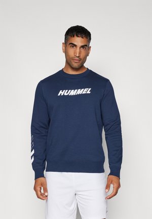 Navy blue sweatshirt made of cotton with long sleeves, features a white "HUMMEL" logo on the front and a geometric pattern along the sleeve.