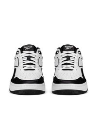 Pár bielych a čiernych Reebok tenisiek, bočný pohľad, s bielymi šnúrkami a logom Reebok na jazyku.