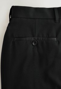 Melni bikses ar gludu tekstūru, kurām ir aizmugurējā kabata, pogu aizdare un jostas cilpas uz vidukļa.