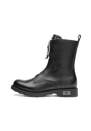 Bottine en cuir noir avec fermeture éclair sur le côté, bout arrondi et semelle texturée. Elle présente un petit talon et des embellissements au niveau de la fermeture éclair.