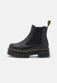 Zwarte chelsea enkellaars gemaakt van leer en elastiek. Voorzien van een robuuste rubberen zool, gele stiksels en een trekband achteraan.
