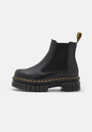 Black chelsea ankle boot made from leather and elastic. Features a chunky rubber sole, yellow stitching, and a pull tab at the back.