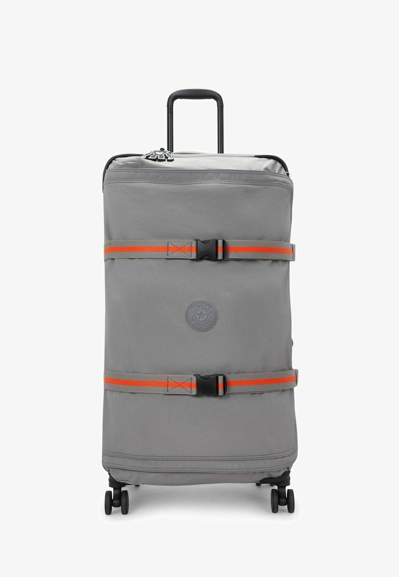 Valise grise à roulettes avec un logo, des accents orange, deux sangles de sécurité et une poignée rétractable. Texture lisse et quatre roues pour la mobilité.